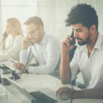 Employees in a Dallas-Fort Worth office using desk phones and laptops — representing the business communication environment NTI Technologies cloud phone systems are designed to support