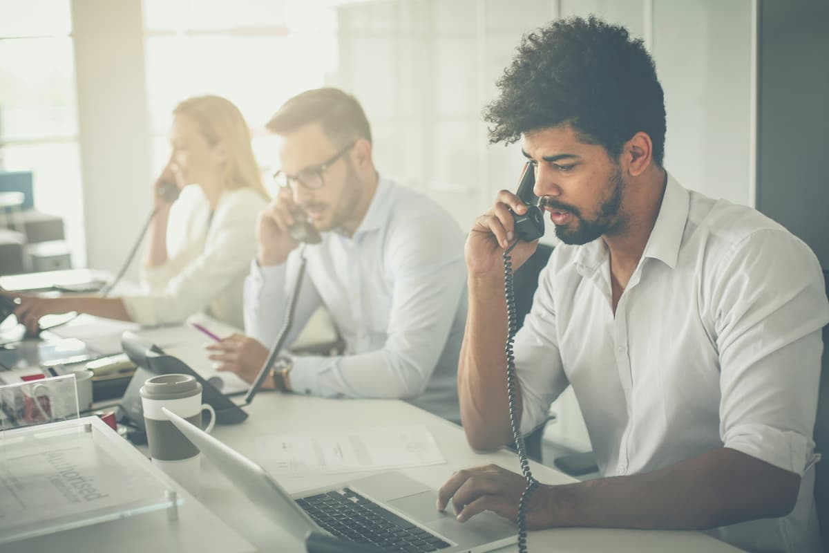 Employees in a Dallas-Fort Worth office using desk phones and laptops — representing the business communication environment NTI Technologies cloud phone systems are designed to support