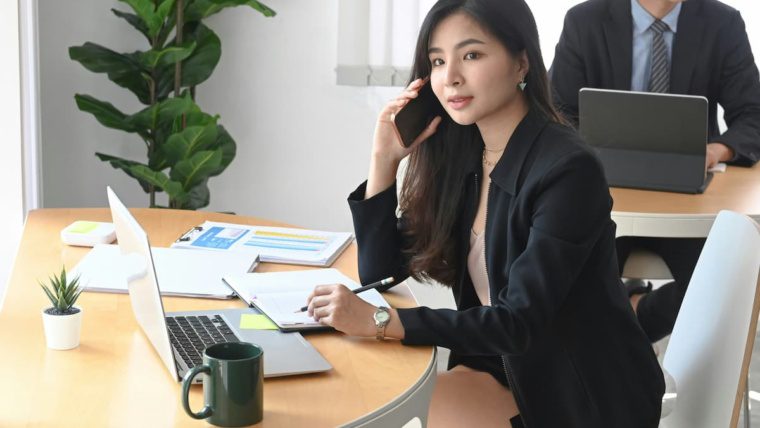 Business professional using cloud phone system on mobile device in modern Dallas Fort Worth office comparing hosted VoIP vs on-premise PBX options