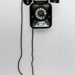 Vintage black rotary wall phone representing outdated POTS copper phone lines being discontinued by carriers