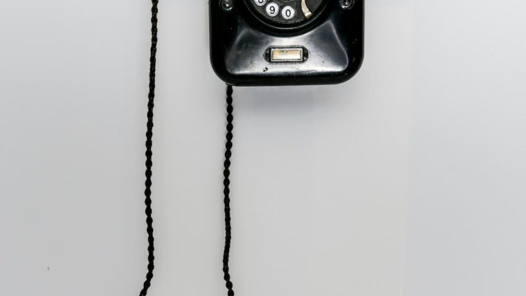 Vintage black rotary wall phone representing outdated POTS copper phone lines being discontinued by carriers