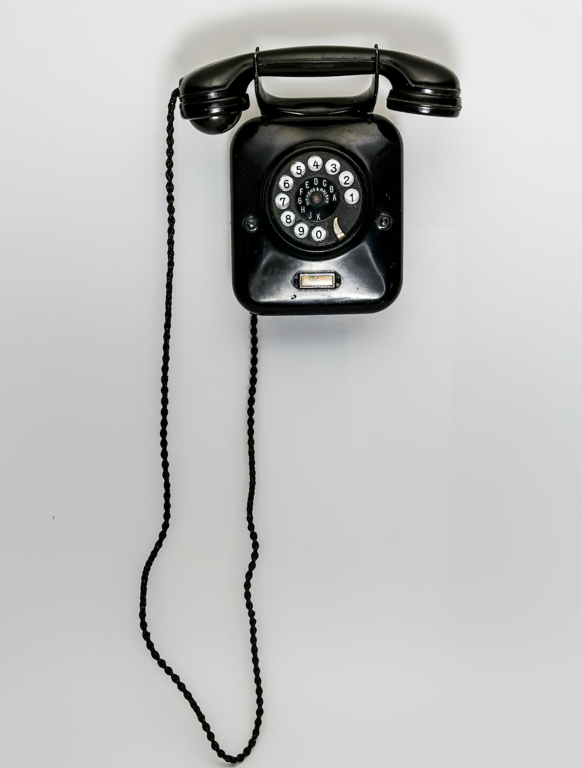 Vintage black rotary wall phone representing outdated POTS copper phone lines being discontinued by carriers