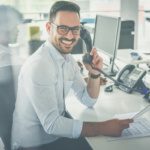 Dallas Fort Worth business professional on modern office desk phone reviewing documents showing signs it may be time to upgrade outdated PBX phone system