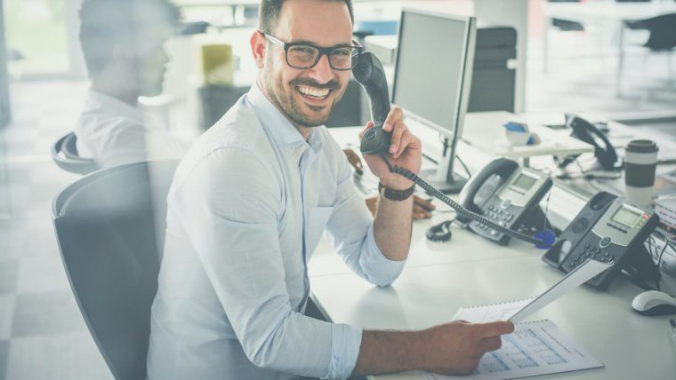 Dallas Fort Worth business professional on modern office desk phone reviewing documents showing signs it may be time to upgrade outdated PBX phone system