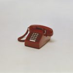 Vintage red push-button desk phone representing outdated POTS copper landlines being replaced by VoIP and cloud phone systems in Dallas Fort Worth