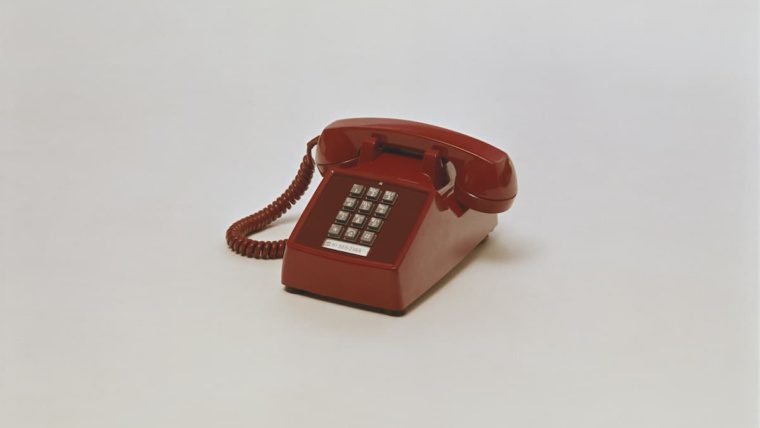 Vintage red push-button desk phone representing outdated POTS copper landlines being replaced by VoIP and cloud phone systems in Dallas Fort Worth