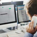 Business owner reviewing phone system costs on computer in Dallas-Fort Worth office