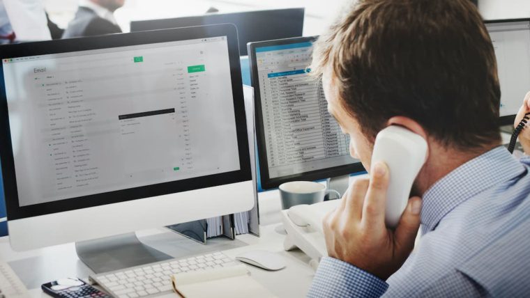 Business owner reviewing phone system costs on computer in Dallas-Fort Worth office