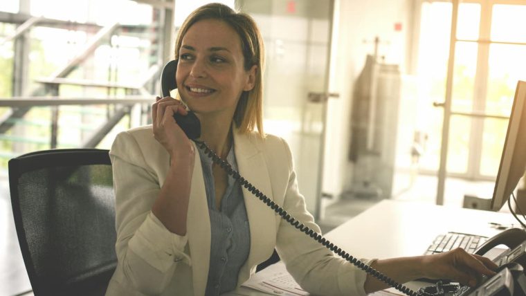 Healthcare front desk professional using a HIPAA-compliant healthcare phone system in a Dallas-Fort Worth medical office