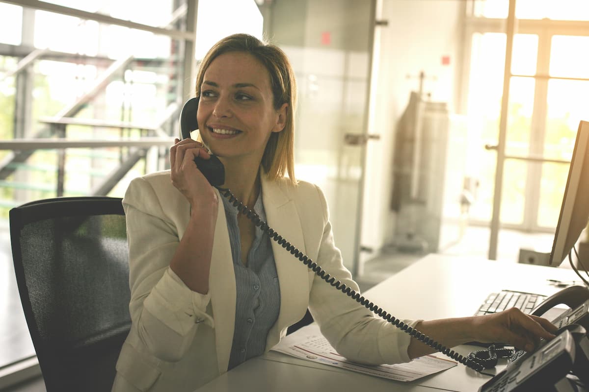 Healthcare front desk professional using a HIPAA-compliant healthcare phone system in a Dallas-Fort Worth medical office