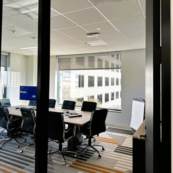 Modern conference room with meeting table, chairs, and wall-mounted display.