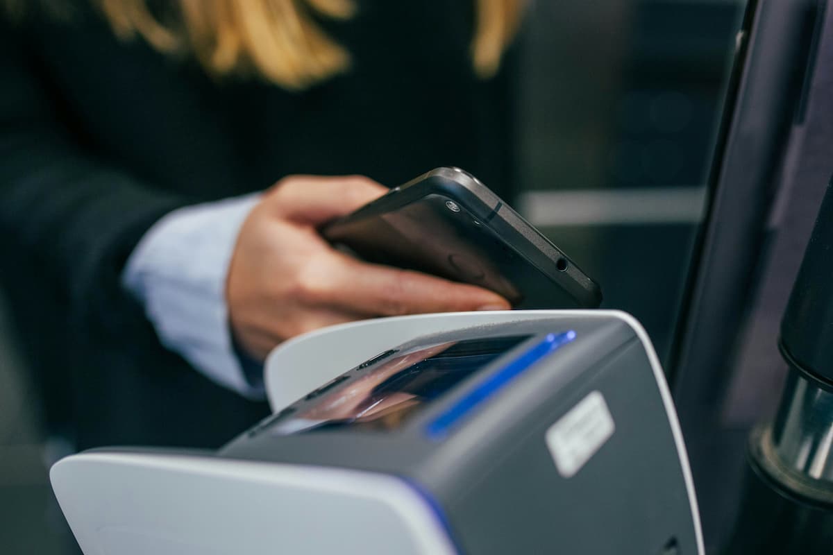 Access control credentials Dallas — person tapping a smartphone to an NFC reader as a mobile access control credential, representing the mobile credential options NTi Technologies configures through Brivo and Avigilon Alta for DFW commercial offices
