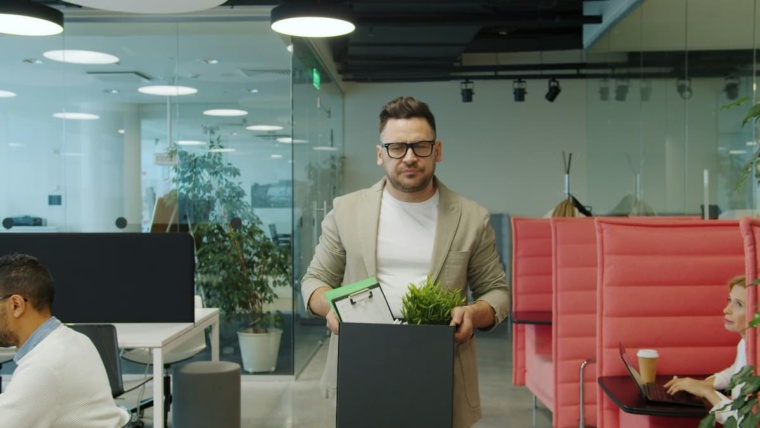Access control offboarding Dallas — terminated employee carrying a box of personal belongings out of a commercial office, representing the physical security risk NTi Technologies addresses through automated credential revocation via Brivo and Avigilon Alta