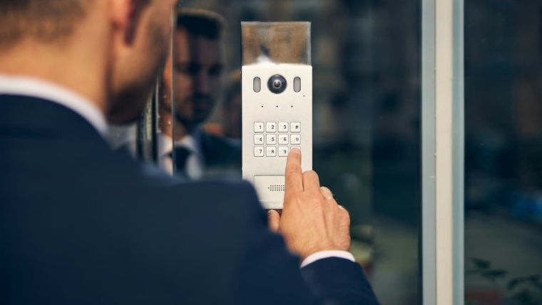 Cloud access control Dallas — business professional entering PIN on a commercial door keypad and camera unit installed by NTI Technologies for a DFW office building
