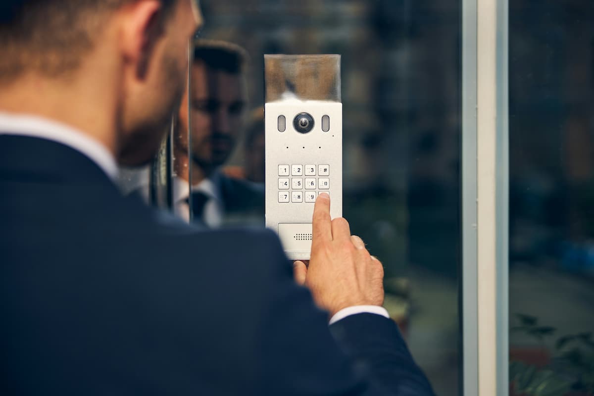 Cloud access control Dallas — business professional entering PIN on a commercial door keypad and camera unit installed by NTI Technologies for a DFW office building