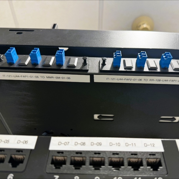 Close-up of labeled patch panel ports and cable connections.