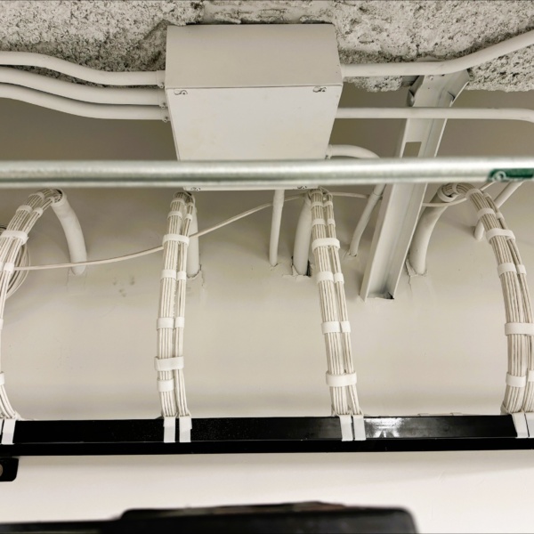 Close-up of bundled cables entering ceiling conduit and junction box.