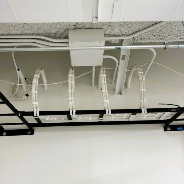 Overhead structured cabling routed neatly through a black cable tray.
