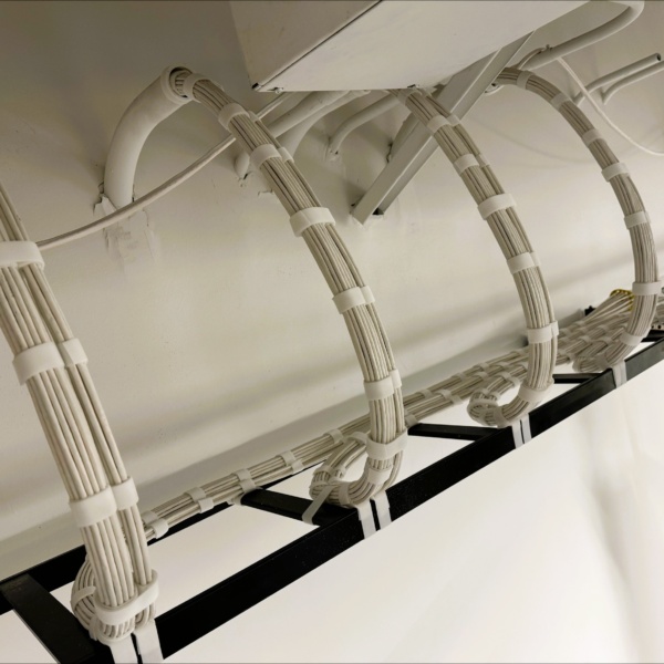 Close-up of bundled cables routed through ceiling conduit.