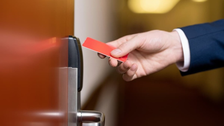 Tailgating prevention Dallas — business professional presenting a key card to a commercial door reader, representing the controlled entry points where NTi Technologies configures tailgating detection through Brivo Security Suite and Avigilon Alta