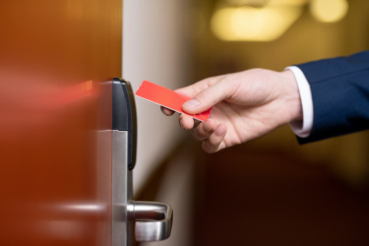 Tailgating prevention Dallas — business professional presenting a key card to a commercial door reader, representing the controlled entry points where NTi Technologies configures tailgating detection through Brivo Security Suite and Avigilon Alta