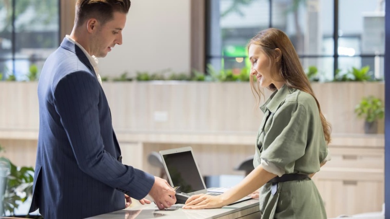 Visitor management system Dallas — business visitor checking in at a modern commercial office reception desk, representing the digital visitor management systems NTi Technologies installs for DFW offices