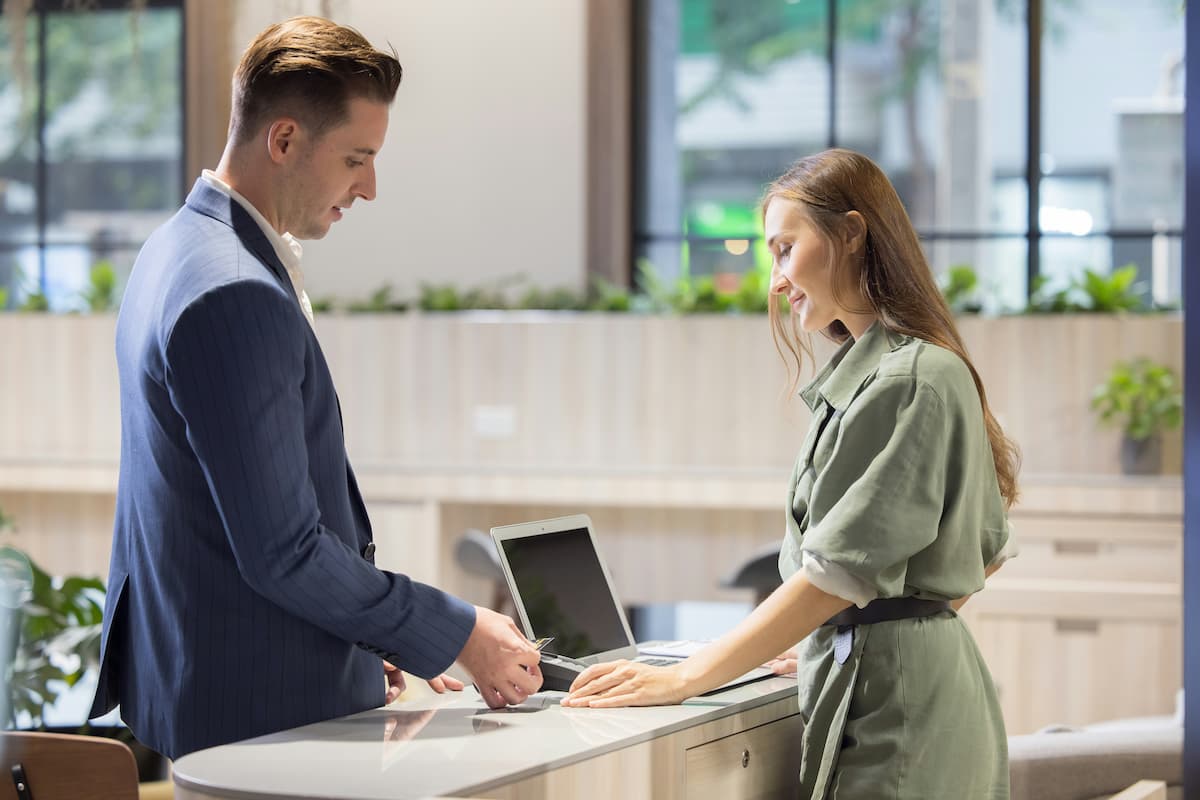 Visitor management system Dallas — business visitor checking in at a modern commercial office reception desk, representing the digital visitor management systems NTi Technologies installs for DFW offices